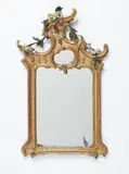 Johann Michael Hoppenhaupt d.Ä., A Friderician giltwood mirror, Carved softwood, painted and gilded over red bole and plaster ground, replaced mirror pane. Concave moulded frame with rocaille engravings and asymmetrical C-scroll terminal, entwined by coloured flowering tendrils. Shortened, retouches and subsequent losses to the polychromy. H 94, W