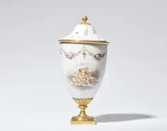 Werner & Mieth, A milk glass potpourri, White glass with polychrome painted decor, ormolu mountings, softwood. Tapering vase with a pierced domed lid. Decorated on one side with putti flying over clouds and playing with flowers. The upper rim with floral garlands, the lid with scattered flowers. The base, foot, shaft, inner ring of the lid and berry finial of bronze. Two restored chips to the rim of the lid. A reattached breakage to the upper back edge of the vase. H
