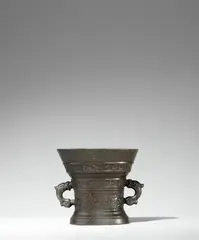 Hendrick Wegewart, jr., A Dutch mortar from 1609, Golden brown cast bronze with chocolate brown patina. Decorated with one thinner and one thicker band of arabesques with acanthus leaves and delicate tendrils. The upper section with a broad banderole inscribed in Latin capital letters: “LOF GODT VAN AL Ao 1609”. The handles formed as dolphins. H 13.1, D