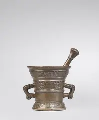 Werkstatt Hachmann, A rare Hachmann mortar and pestle, Golden brown cast bronze with chocolate brown patina. Decorated on both sides with shields supported by winged demi-figures and putti bearing "house marks". Inscribed below the rim and above the base in Gothic minusculae on wide banderoles: "cuimera ruddenscheitz myn hape steit in godt", and "int jaer ons heren m vc lxxiiii". With two zoomorphic handles. Associated double pestle with nodus, engravings and beautiful identical patina. With minor dents around the rim. H 13.5, D