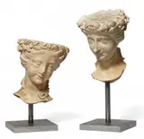 Probably Burgundy 16th century, Two female heads carved from limestone, Limestone, carved in the round, with minimal remains of partial polychromy. These two heads of women crowned with garlands of flowers are broken off at the necks. The pieces were designed for a slightly lowered viewpoint and the tops of the heads are flattened, indicating that they may have been designed for decorative brackets. Wear with minor losses. Mounted on a modern metal stand. Height 24 and