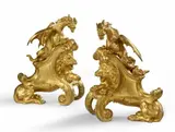 Charles Cressent, A pair of ormolu fire dogs with lions and dragons, Finely chased bronze models cast with integral slanted plinths. The backs hollow. H 37, W 31.5 and H 36.5, W