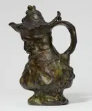 “Le vin” A bronze jug by Philippe Wolfers, A bronze jug by Philippe Wolfers, “Le vin”, Cast bronze with blackish green patina over copper gold patina. Baluster form vessel with a protruding base, spout and branch shaped handle, the domed lid formed from vine leaves with a finial designed as a bunch of grapes. With a bearded relief mascaron below the spout. Engraved “Ph. Wolfers” on the reverse below the handle. H