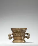 Werkstatt Hachmann, An early Hachmann mortar with a “house mark”, Thinly cast bronze with honey brown patina. Decorated on the display side with a coat-of-arms bearing a “house mark” supported by two winged demi-figures. With a wide banderole below the rim inscribed in Gothic minuscule: “int iaer ons heren m vc lviii”. With two zoomorphic handles. The base slightly rounded due to use, horizontal cracks to both sides above the base, some minor dents around the rim. H 13, D