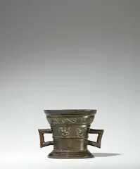 Werkstatt Hachmann, A late Hachmann mortar with dog and rabbit motifs, Cast bronze with chocolate brown patina. The display side decorated with a vacant coat-of-arms supported by winged demi-figures. Below the rim a broad banderole inscribed in Latin capital letters: “INT IAR ONS HEREN 1584”. With two angular faceted handles. Slight verdigris in the indentations. H 11, D