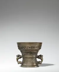 Hendrick Wegewart, jr., A dated Dutch mortar with a romantic inscription, Golden brown cast bronze with honey coloured natural patina. With a central horizontal moulding, two bands of acanthus, and half-length grotesque figures flanked by cornucopias and arabesque tendrils. With a broad inscription in capital letters below the rim: “AMOR VINCIT OMNIA ANNO 1606”. With zoomorphic handles. H 13.5, D