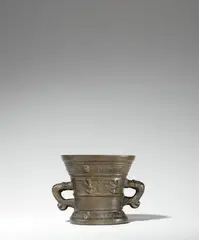 Werkstatt Hachmann, A Hachmann mortar inscribed “IN DEO SPES MEA”, Reddish gold cast bronze with dark brown patina. The display side decorated with a vacant coat-of-arms supported by winged demi-figures. With two wide banderoles below the rim and above the base inscribed in Latin capital letters: “ANNO DOMINI M VC LXXV” and “IN DEO SPES MEA”. With two zoomorphic handles. Some small cracks around the lower section, minor abrasions. H 11.1, D