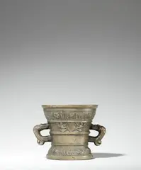 A Hachmann mortar made for Johan die Ruey, A Hachmann mortar made for Johan die Ruey, Golden brown cast bronze with natural patina. The display side decorated with a vacant coat-of-arms supported by winged demi-figures. With two wide banderoles below the rim and above the base inscribed in Gothic minuscule: “johan die ruey errem syn huisfrouw” and “int iaer ons heren m vc lxxi”. With two zoomorphic handles. Minor dents around the rim, some small casting faults to the base. H 12.4, D