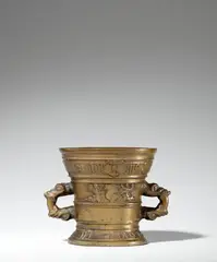 Werkstatt Hachmann, A later Hachmann mortar with an inscription, Golden brown cast bronze with honey coloured natural patina. The display side decorated with a vacant coat-of-arms supported by winged demi-figures. With two wide banderoles below the rim and above the base inscribed in Gothic minuscule and Latin capital letters: “int iaer ons heren m vc lxxx4” and “IN DEO SPES MEA”. The handles formed as double-headed dragons. Minor dents around the rim. H 14.5, D