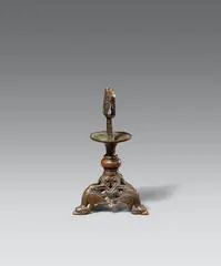 Hildesheim second half 12th century, A Hildesheim bronze dragon candelstick, second half 12th century, Cast bronze with old patina. The base of this tripod candlestick is decorated with stylised dragons beneath a round pommel and a wide, protruding drip pan. The piece displays strong stilistic similarity to a dragon candlestick in the Diözesanmuseum in Münster, which Otto von Falke (op. cit.) published as a Westphalian work dating to around 1200. Very minor wear and dents. The iron pricket presumably an older replacement
