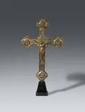 Maasland, A 14th century processional cross, presumably Maasland, Cast bronze on a wooden base with engraved brass mountings and remains of original gilding. The Corpus Christi is here placed separately against the square shaped centre of the cross and the four symbols of the evangelists against the quatrefoil terminals. The front of the cross is engraved with the Lamb of God in the centre and stylised tendrils on the beams. The engravings of the reverse repeat the symbols of the evangelists and tendrils whilst the centre shows the Veil of Veronica with the Vera Icon. The horizontal beam behind the Corpus reattached with solder. With dents and abrasions. Mounted on a wooden plint