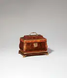A bombé form box by Abraham Roentgen, A bombé form box by Abraham Roentgen, Burr walnut, rosewood and cherry veneer on oak and solid cherry with fire-gilt bronze, brass and steel mounts. Of rectangular shape with hinged top and handle. The larger base resting on four curved bracket feet. A finely engraved cartouche-shaped lock plate opens by pushing a button which activates a spring mechanism to reveal the keyhole. The box contains a shallow removable tray with two cherry wood compartments (with a horizontal crack) above a large unveneered compartment and a shallow secret compartment in the right side of the base which can be opened by pushing a rectangular button placed int he inner right side. All faces decorated with finely grained veneers framed by brass and pale rosewood stringing. The convex edges and moulded base accentuated by brass fillings. The lid inset with a small brass cartouche engraved with a dragon. H 18.1, W 23.5, D