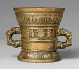 A dated Hachmann mortar with dog and rabbit decor, A dated Hachmann mortar with dog and rabbit decor, Golden brown cast bronze with natural patina. The display side decorated with putti supporting a vacant shield. With broad bands below the rim and around the base inscribed in Gothic minuscule: "myn haus steit allein in godt" and "int jaer ons heren m vc lxxv". Two handles formed as double-headed dragons. Slight wear to the decor. H 14.9, D