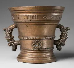 A large early Hachmann mortar, A large early Hachmann mortar, Golden brown cast bronze with natural patina. With a broad banderole in Gothic minuscule below the rim "anno domini m ccccc xl". A twisted moulding surrounding the centre above two arabesque ornaments. The handles formed as finely modelled dragon's heads. A horizontal plaque to the lower section. H 23, D