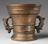 A large early Hachmann mortar, A large early Hachmann mortar, Golden brown cast bronze with natural patina. With a broad banderole in Gothic minuscule below the rim "anno domini m ccccc xl". A twisted moulding surrounding the centre above two arabesque ornaments. The handles formed as finely modelled dragon's heads. A horizontal plaque to the lower section. H 23, D