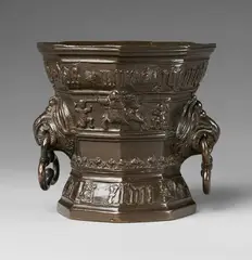 A highly important Hachmann mortar, A highly important Hachmann mortar, Golden brown cast bronze with dark brown patina. Conical form of octagonal section with waisted base. The outer surface divided horizontally, a banderole with an inscription in Gothic minuscule below the rim "godt hefft ghevucht das myr ghenught" and around the base "anno domini m vc l vii". Unusual handles formed as griffon's heads holding three lobed rings. H 15.1, D