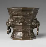 A highly important Hachmann mortar, A highly important Hachmann mortar, Golden brown cast bronze with dark brown patina. Conical form of octagonal section with waisted base. The outer surface divided horizontally, a banderole with an inscription in Gothic minuscule below the rim "godt hefft ghevucht das myr ghenught" and around the base "anno domini m vc l vii". Unusual handles formed as griffon's heads holding three lobed rings. H 15.1, D