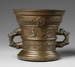 A dated Hachmann mortar with dragon handles, A dated Hachmann mortar with dragon handles, Cast bronze with fine golden brown patina. Decorated with a vacant heraldic shield supported by winged half-figures beneath a medallion with the Veil of Veronica. A band of fleur-de-lys surrounds the lower border. Dated "anno domini mcccccxlviii" in Gothic minuscule and with a dog chasing a rabbit below the rim. H 16, D