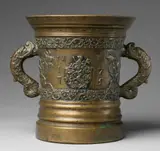 Foundry Reinhard, A large Tyrolese mortar with dolphin handles, Golden brown cast bronze with traces of silver plating and slightly mottled patina. Cast with two bands of rocaille ornament and a heraldic shield to the display side, monogrammed "IAW" and dated "1775", flanked by insects and naturalistic leaf motifs. With acanthus clasped dolphin handles. A horizontal crack to the lower section. H 28.5, D