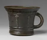 Foundry Crescimbeni, A rare Italian ribbed mortar, Cast bronze with dark brown patina. Squat, slightly tapering form with flared rim. Cast with six twisted columns beneath Gothic capitals and the initials "S E". The caster's signature inscribed around the rim "CRESCENBENI ME FECIT". C-shaped handles with braided appliques. H 12.8, D
