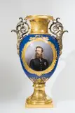 A huge royal Berlin KPM porcelain vase with a portrait of Crown Prince Frederick William and a view of the Kronprinzenpalais by Königliche Porzellanmanufaktur Berlin Kpm, Model no. 1685. A large, round vase fired in three parts and mounted via large bronze foliate handles and a beaded ring., offered Apr 2018