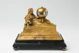 Hanns Buschmann, An Augsburg figural clock "Urania", Gilt copper and bronze, engraved dial and silver hands, ebonised wood base and later red velvet to the interior. One day movement with hourly striking to a bell. Designed as a figure of Urania, the muse of astrology, recumbent upon a moulded gilt copper plinth upon a contrasting ebonised wood base. The sceptre in her right hand forms the hour hand of the clock, pointing towards the hour indices on the equatorial band of the globe on a column. Engraved to the upper right of the plate "Hannß Buschmann A". H 16.3, W 20, D