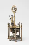 Hanns Buschmann, An Augsburg figural clock with an African man and an ostrich, Gilt bronze and copper, engraved silver, brass. Later day-running movement with hourly striking to a bell. The movement and figures attached to an upper panel supported by six columns. Next to a diminutive ostrich, an African man dressed as a Roman soldier holding a sabre stands with his hand resting upon a palm tree supporting the globe-shaped clock. The equator forms the hour aperture, with a single stationary hand dropping down from a wreath surrounding the globe. Engraved to the upper panel: Hannß Buschmann A. (presumably originally the plate). The movement, arrow, and lower panel later additions. H