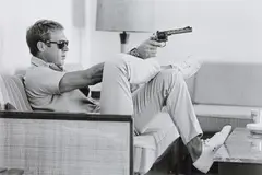 John Dominis, Steve McQueen aims a pistol in his living room, CA, 1963, Posthumous gelatin silver print, printed