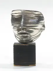 TWARZ ZAWOALOWANA by Igor Mitoraj, 1977, metal srebrzony, podstawa drewniana, offered Aug 2024