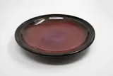 Michael Lucas, Red platter, stoneware with tenmoku glaze giving to a pool of bright red glaze to the centre