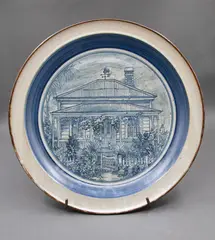 Phoenix Pottery (Michael Lucas & Jill Totty), ‘Flower Cottage’, Devonport Centennial Plate, glazed ceramic, on a metal stand