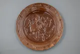 Crown Lynn Wharetana Ware, 'Hei Tiki' wall plate, brown glazed ceramic (with two suspension holes to foorim)