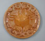 Crown Lynn Wharetana Ware, 'Taniwha' wall plate, brown glazed ceramic (with two suspension holes to foorim)