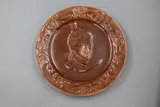 Crown Lynn Wharetana Ware, 'Maori Chief' wall plate, brown glazed ceramic (with two suspension holes to foorim)