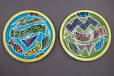 Two circular plates by Warren Tippett, with polychrome abstract and fish decoration on blue and green grounds (hairline), sold Jun 2026