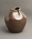 Barry Brickell, Large 'Fatso' vase, stoneware with speckled persimmon glaze thinning around the rim, the rim pinched on two sides with stylized characterful beak forms and applied rivet detail