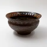 Barry Brickell, Sculpted bowl, grogged clay stoneware with tenmoku glaze, relief cross pattern around the flaring rim (minor fritting to the rim)