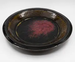 Len Castle, Large charger, stoneware with dark olive glaze to the well giving to a pool of purple red jun glaze over black glaze to the centre, the rim and exterior with tenmoku glaze