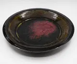 Len Castle, Large charger, stoneware with dark olive glaze to the well giving to a pool of purple red jun glaze over black glaze to the centre, the rim and exterior with tenmoku glaze