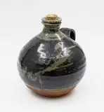 Len Castle, Wine flagon, stoneware of squat ovoid form, celadon wax resist blossom design under tenmoku glaze, original cork stopper