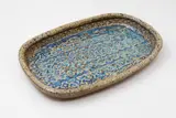 Barry Brickell, Rectangular platter, stoneware with mottled oatmeal glaze giving to a pool of blue glaze to the centre with impressed decoration (flake chip and hairline crack to base)