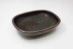 Len Castle, Rectangular platter, stoneware decorated with wax resist stamped design, celadon glaze under tenmoku (cracked)