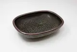 Len Castle, Rectangular platter, stoneware decorated with wax resist stamped design, celadon glaze under tenmoku (cracked)