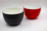 Two large enamel bowls by Kaj Franck for Finel & Arabia, in shiny red and matt black, both with white interior, offered May 2025