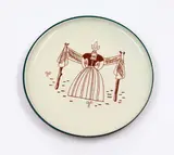 Wall plate by Frank Carpay for Ambacht Volendam, featuring a female figure in traditional dress in brown sgraffitto on cream ground, offered May 2025