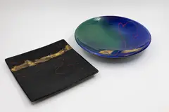 Two platters by Peter Collis, in blue and shiny black, both with gold leaf and enamel red gestural decoration, offered May 2025