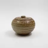 Early small lidded jar by Len Castle, stoneware with light brown salt glaze, with a loose, almost flat lid, fired in the Crum Brickworks kilns, sold May 2025