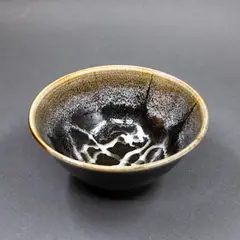 Porcelain bowl by Graeme Storm, with tenmoku glaze with white highlights to the interior, offered May 2025
