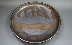 Stoneware charger by Graeme Storm, with manganese glaze with dark gloss gold highlights, offered May 2025