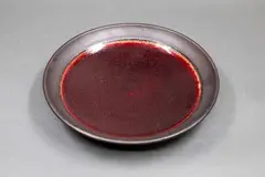 Stoneware dish by Graeme Storm, with rich, gloss copper red glaze to the centre, matt black manganese glaze to the rim and exterior, offered May 2025